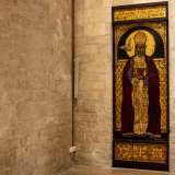 Specularmente al santo di Myra, alla fine del corridoio laterale, un affresco di San Gregorio del 1983 tinge con i suoi accesi toni rosso e oro la spenta muratura di fondo